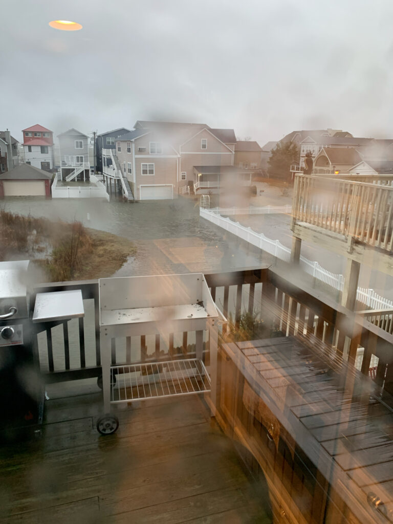 a deck with a railing and a body of water with buildings in the background (MyCoast AI)