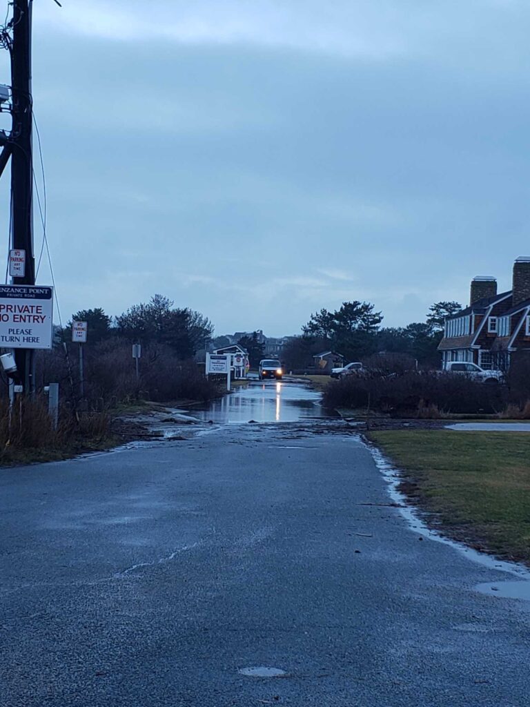 a road with a puddle on the side and buildings on the side (MyCoast AI)