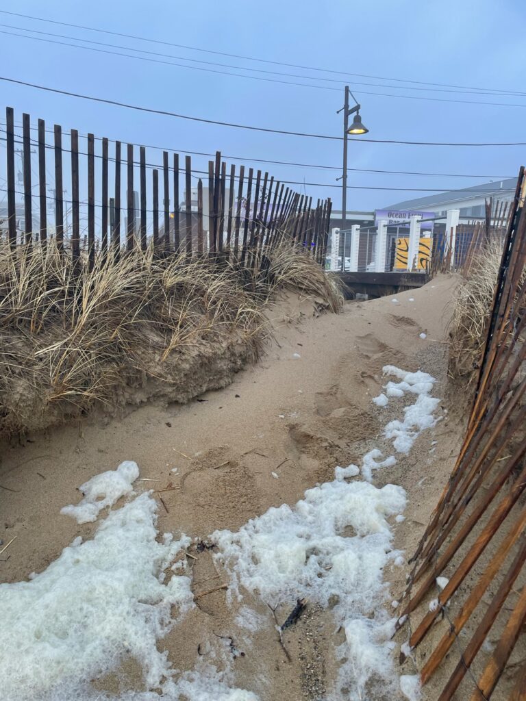 a muddy road with a fence and a building in the background (MyCoast AI)