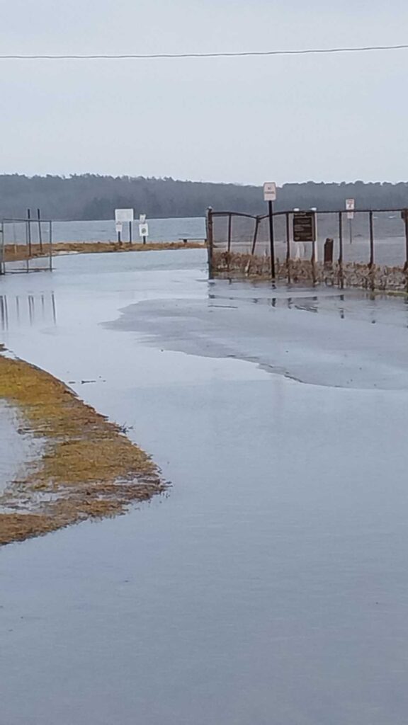 a flooded area with a fence and a sign (MyCoast AI)