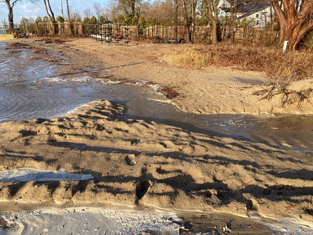 a muddy area with a puddle and a fence in the background (MyCoast AI)