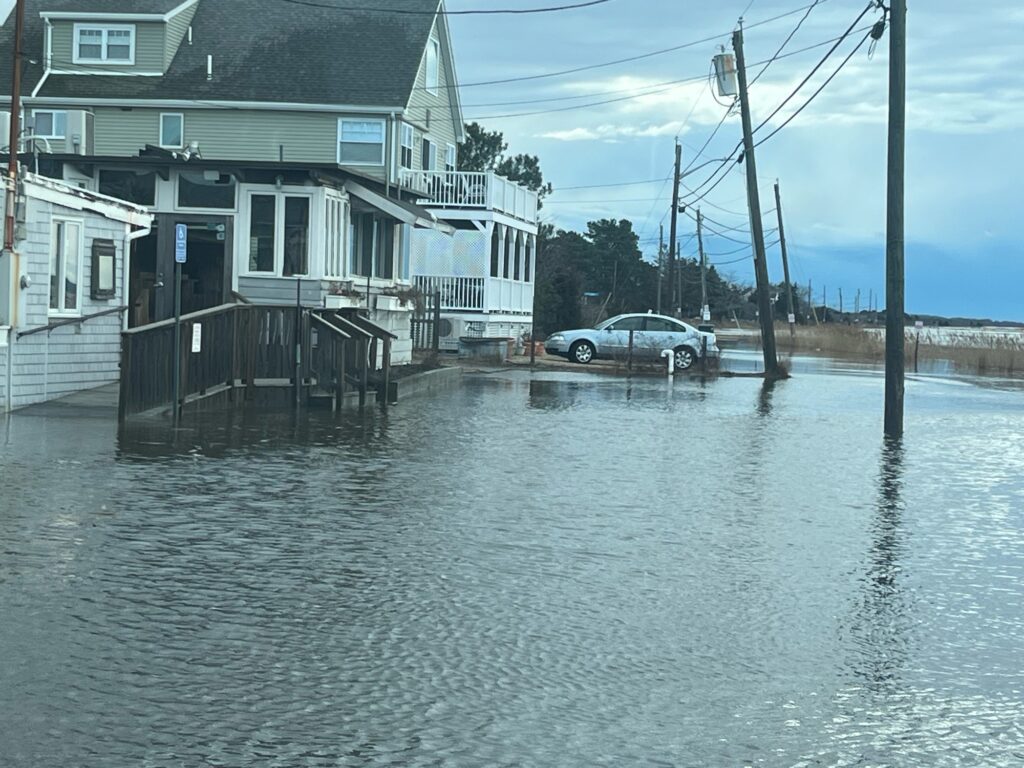 a flooded street with houses and a car parked on the side (MyCoast AI)