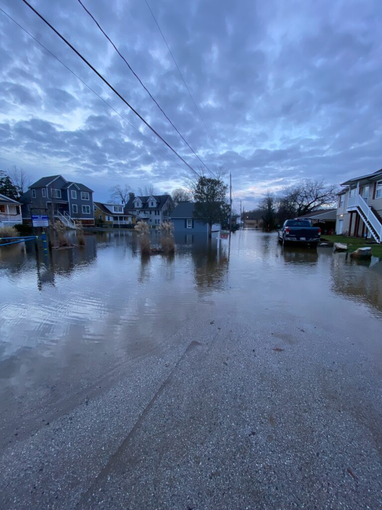 a flooded street with houses and a car parked on the side (MyCoast AI)