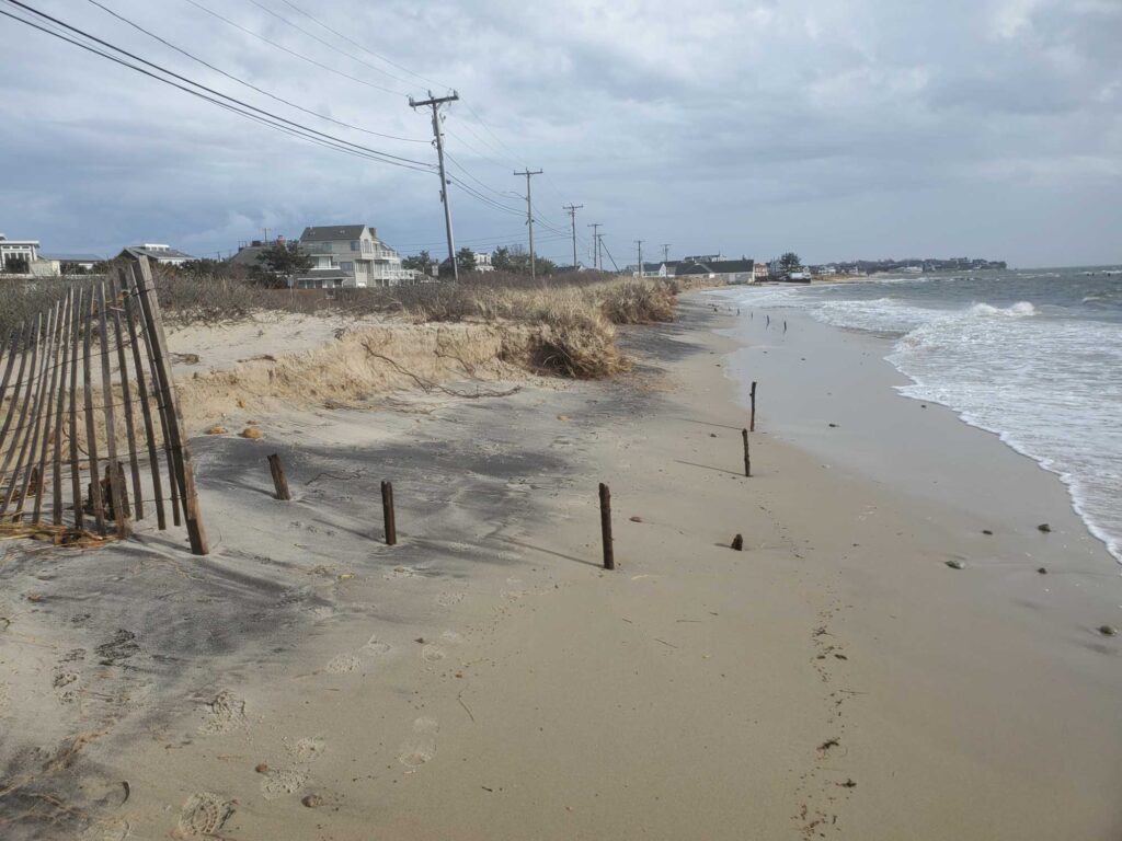 a sandy beach with a fence and a house in the background (MyCoast AI)