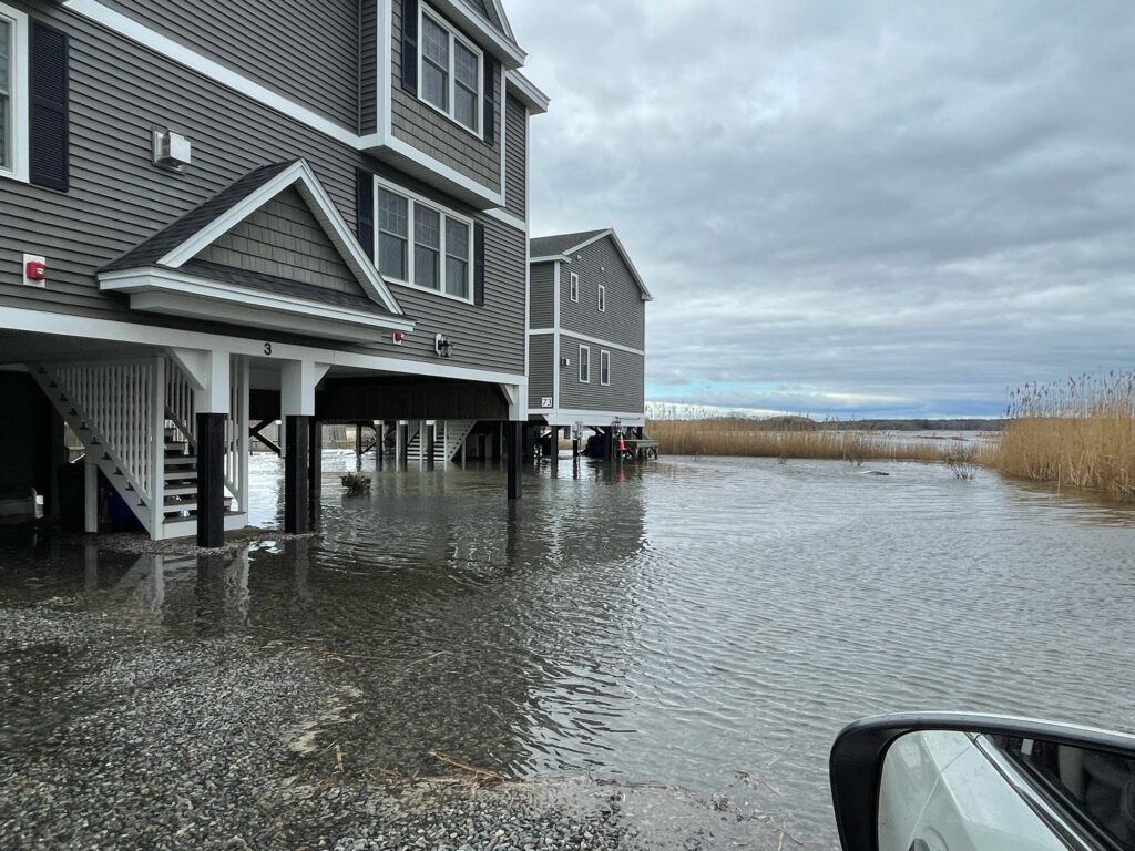 a flooded street with buildings and a car parked on the side (MyCoast AI)