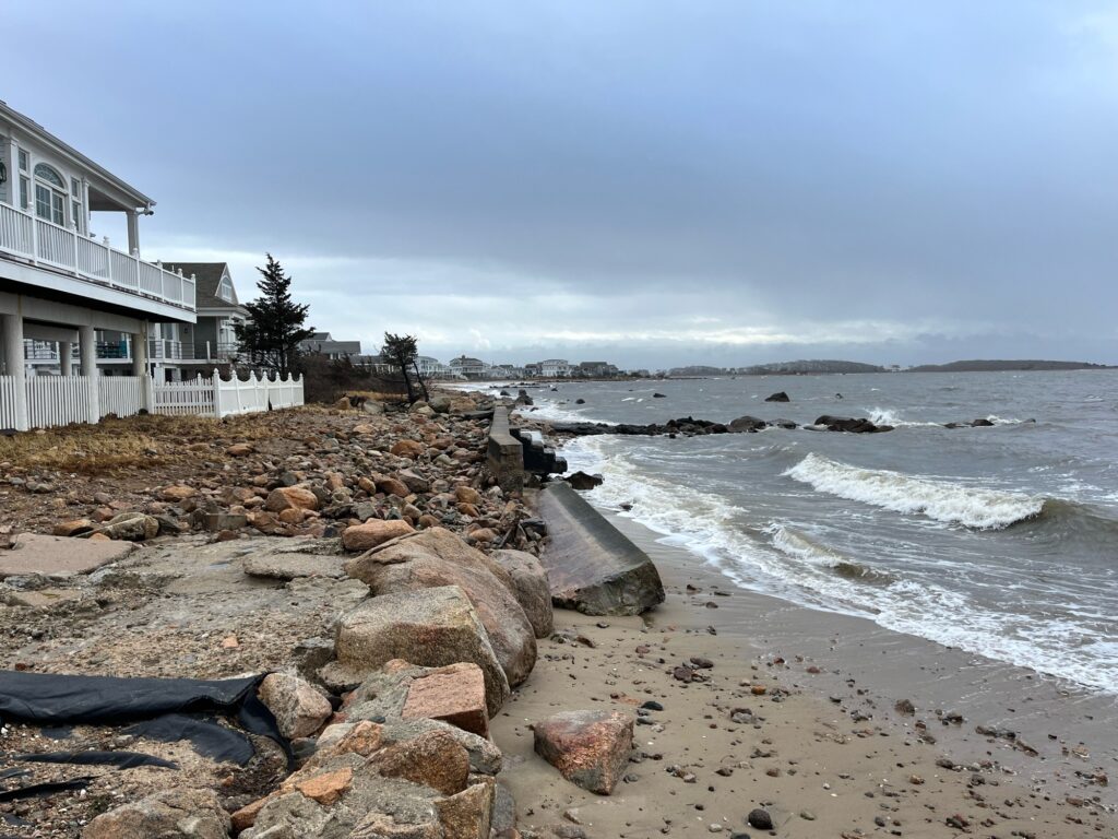 a rocky beach with a house and a large body of water (MyCoast AI)
