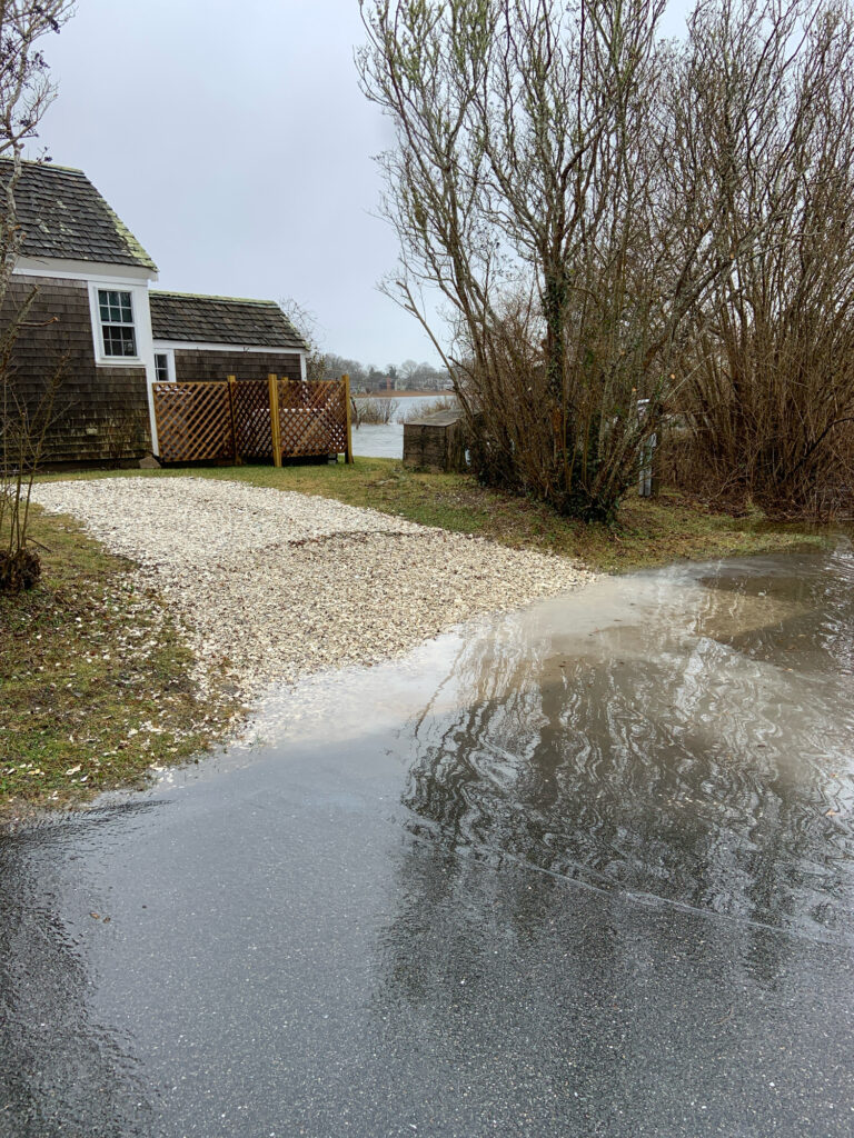 a road with a puddle on the side and houses on the side (MyCoast AI)