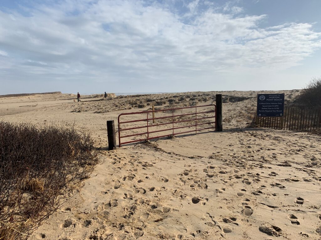 a sandy beach with a fence and a sign (MyCoast AI)