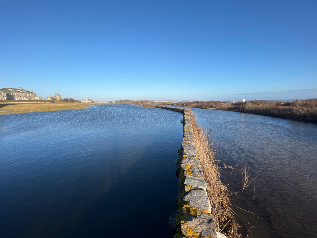 a body of water with a stone wall and grass on the side (MyCoast AI)