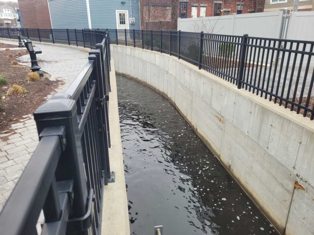 a canal with a fence and a metal railing (MyCoast AI)
