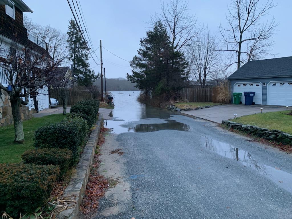 a road with a puddle on the side and buildings on the side (MyCoast AI)