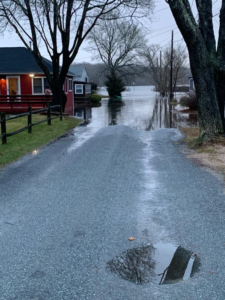 a wet road with houses on either side of it (MyCoast AI)