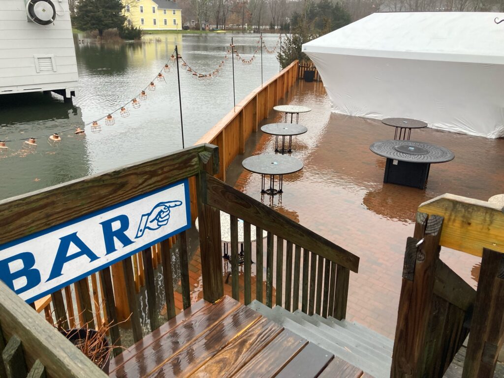 a deck with tables and chairs on it next to a body of water (MyCoast AI)