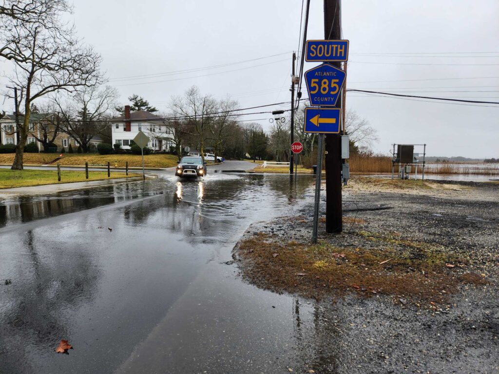 a wet street with a car driving by (MyCoast AI)