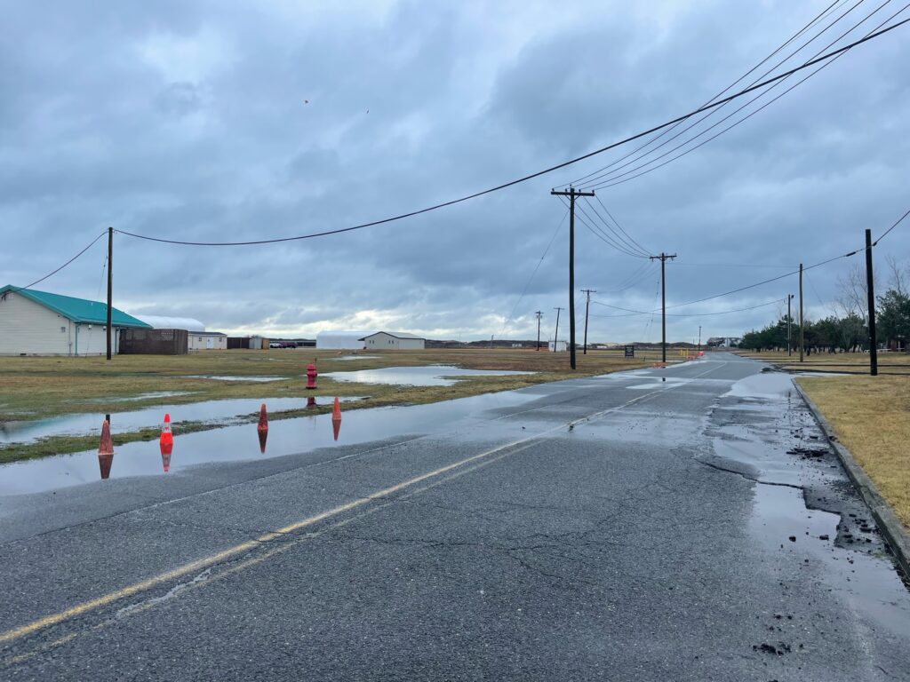 a road with a puddle on the side and power lines above it (MyCoast AI)