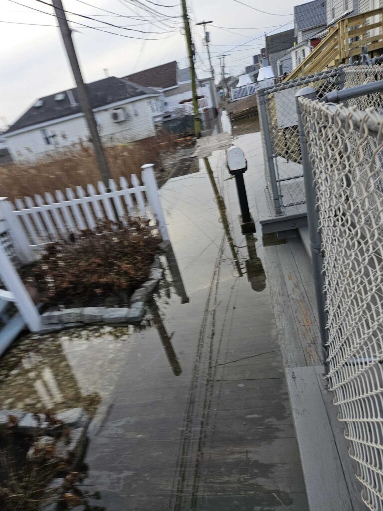 a sidewalk with a fence and a street with snow (MyCoast AI)