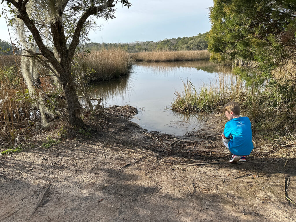 a boy sitting on a dirt path by a river (MyCoast AI)
