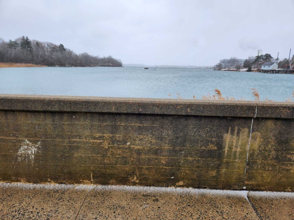 a concrete wall with a body of water in the background (MyCoast AI)