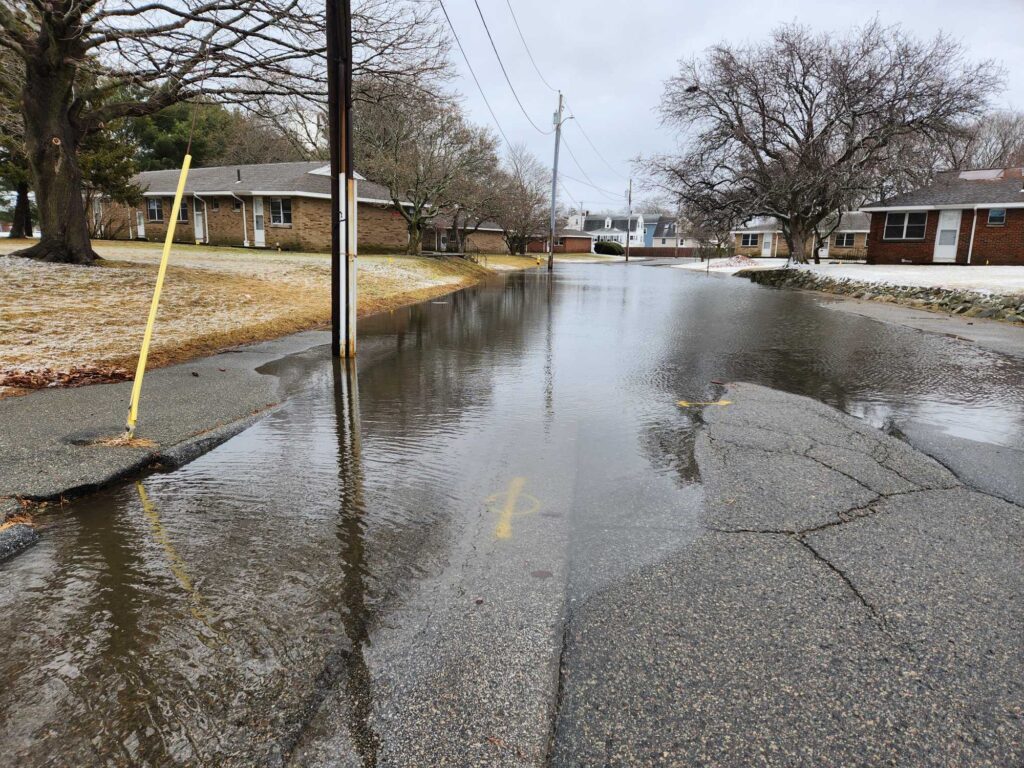 a flooded street with a yellow pole (MyCoast AI)