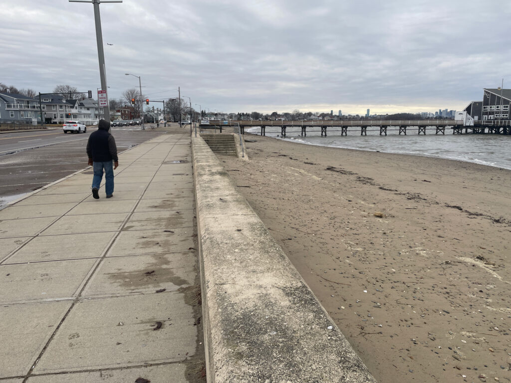 a person walking on a sidewalk next to a beach (MyCoast AI)