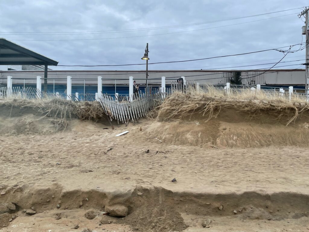a fenced off area with a pile of sticks and a building in the background (MyCoast AI)