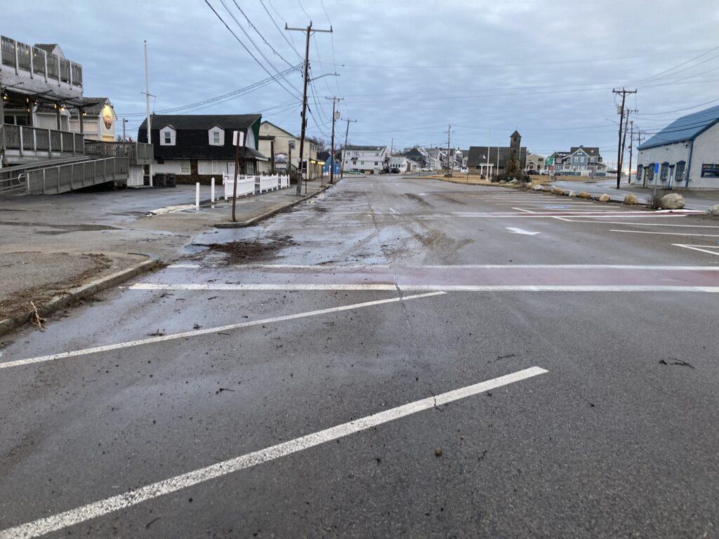a road with a puddle on the side and buildings on the side (MyCoast AI)