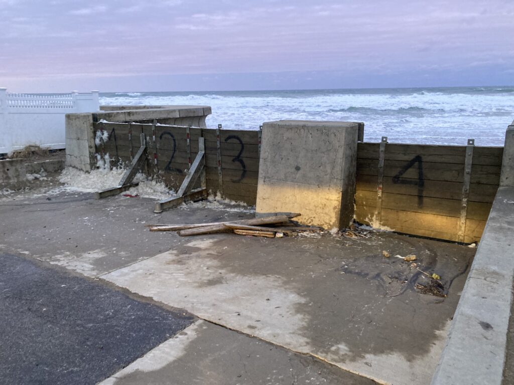 a concrete wall with a metal railing and a body of water in the background (MyCoast AI)