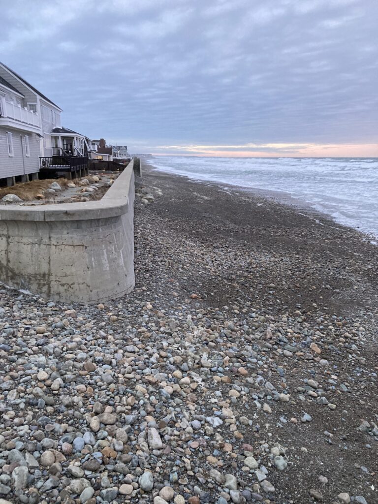 a rocky beach with a building and water in the background (MyCoast AI)