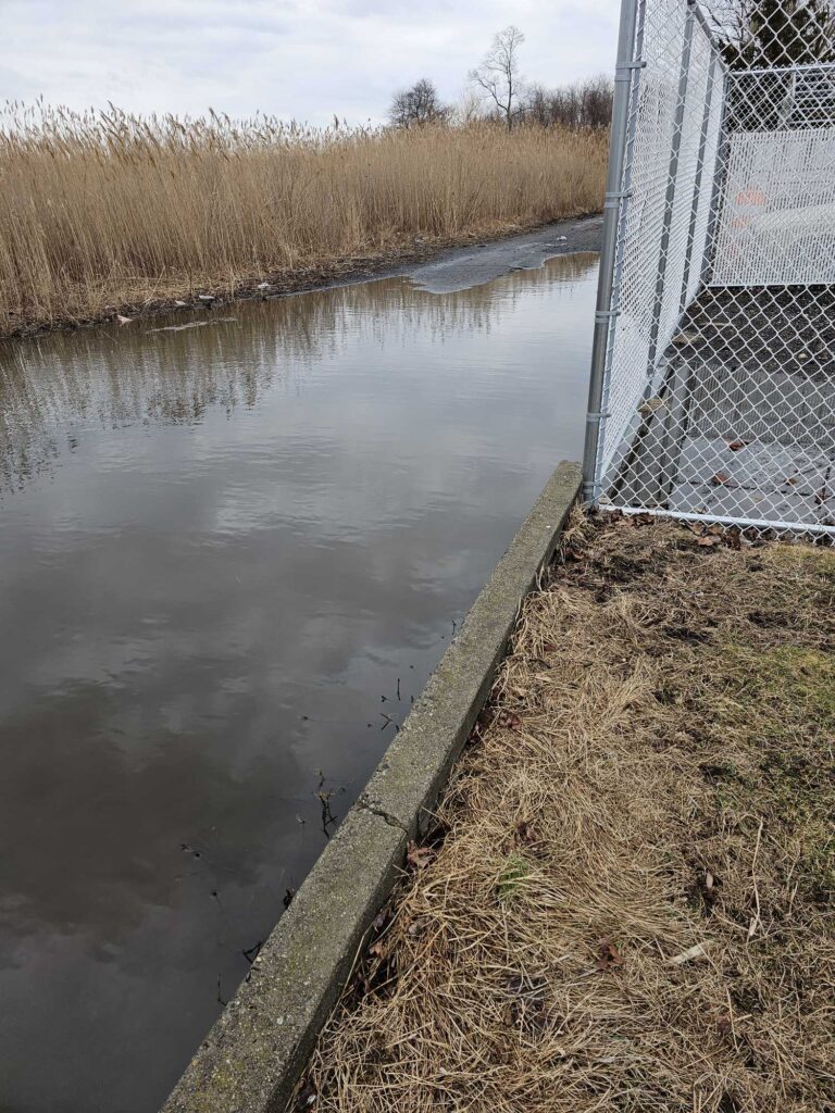 a body of water with a fence and a metal gate (MyCoast AI)