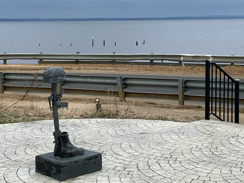 a stone walkway with a bench and a body of water in the background (MyCoast AI)