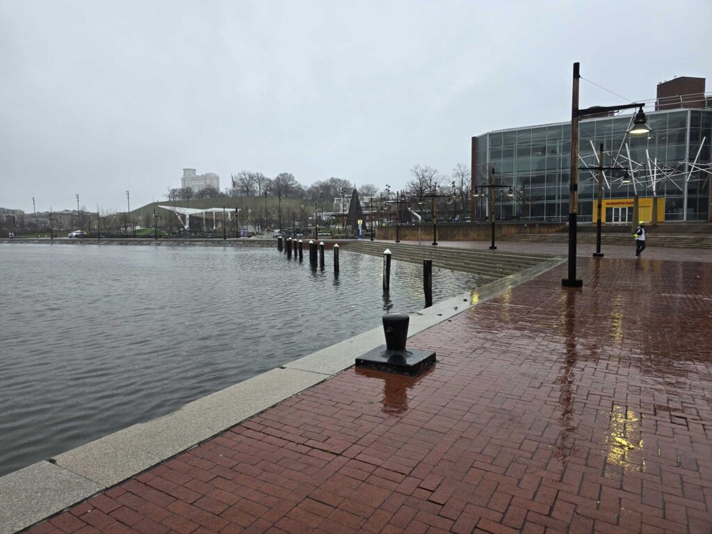 a brick walkway next to a body of water with buildings in the background (MyCoast AI)