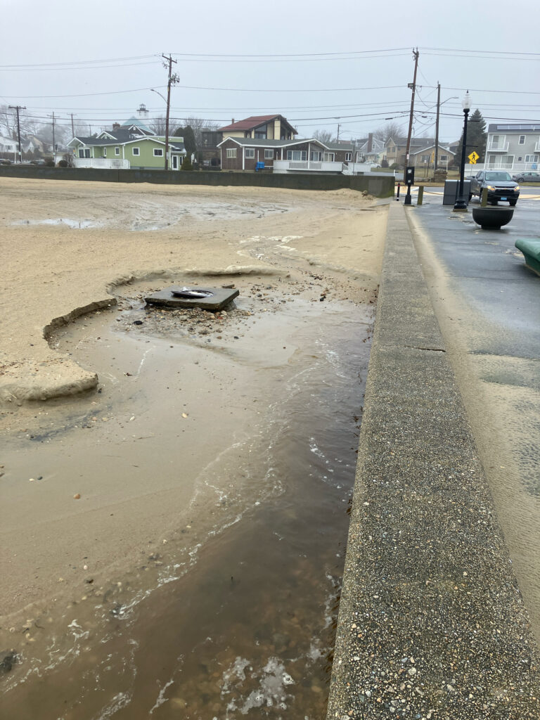 a road with a puddle on the side and houses in the background (MyCoast AI)