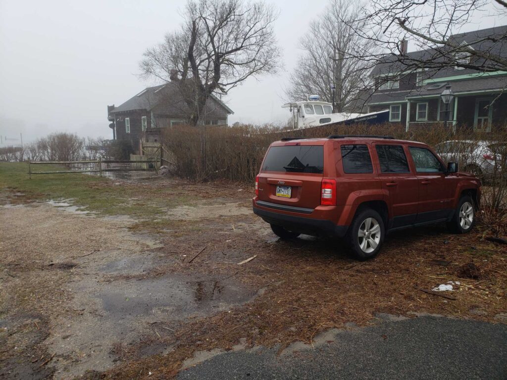 a red car parked on a dirt road with houses in the background (MyCoast AI)