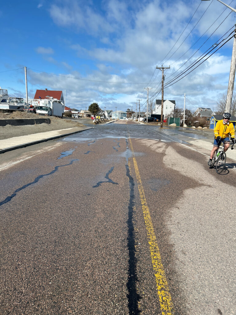 a person riding a bicycle on a road with puddles on the ground (MyCoast AI)
