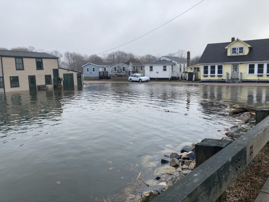 a flooded street with houses and a car parked on the side (MyCoast AI)