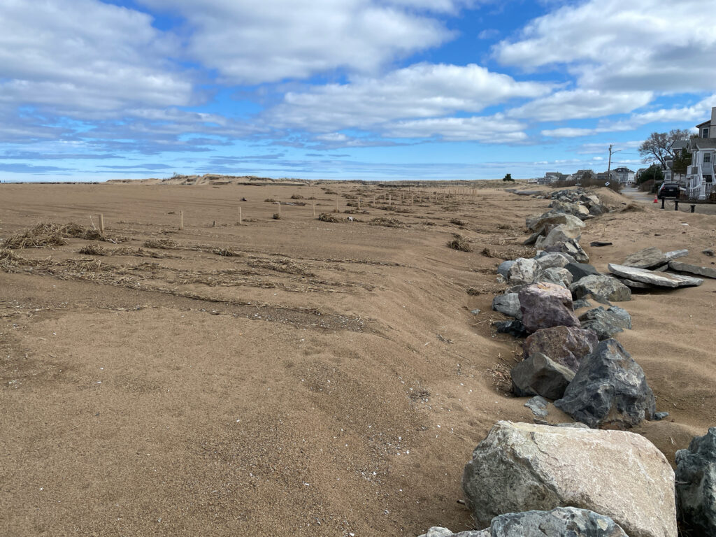 a rocky area with a fence and a sandy beach in the background (MyCoast AI)