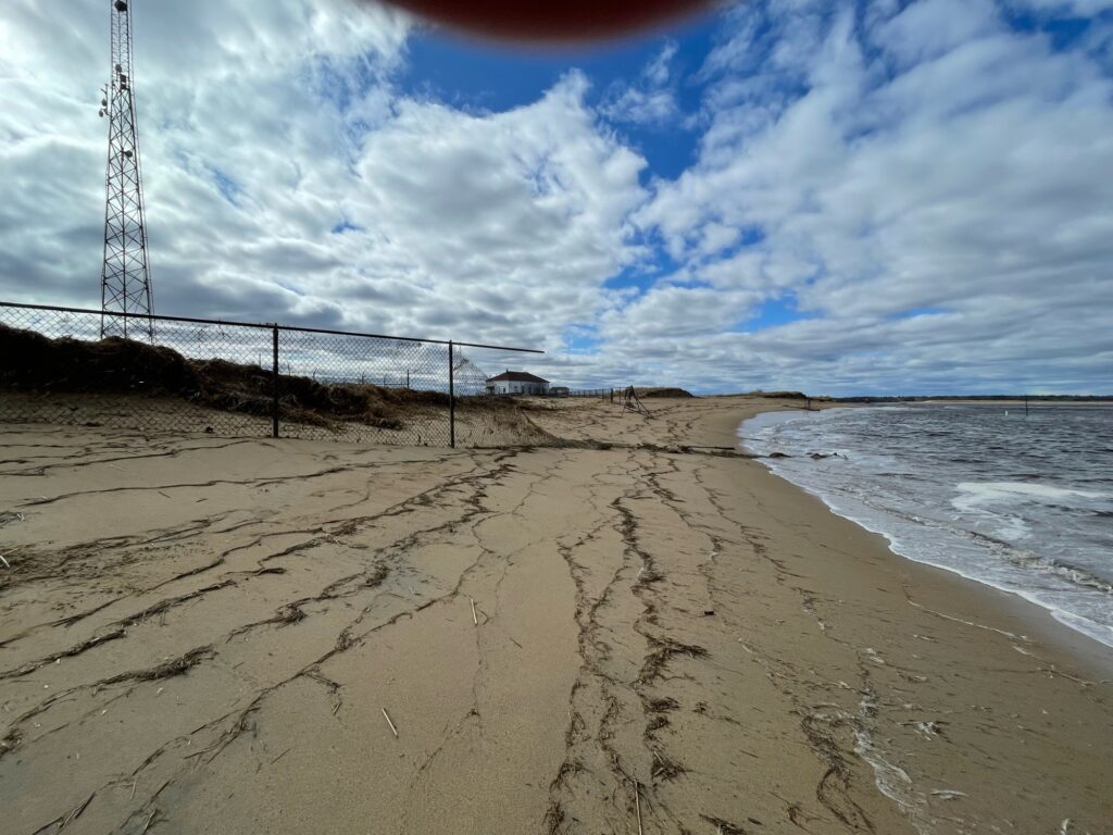 a sandy beach with a fence and a tower in the background (MyCoast AI)