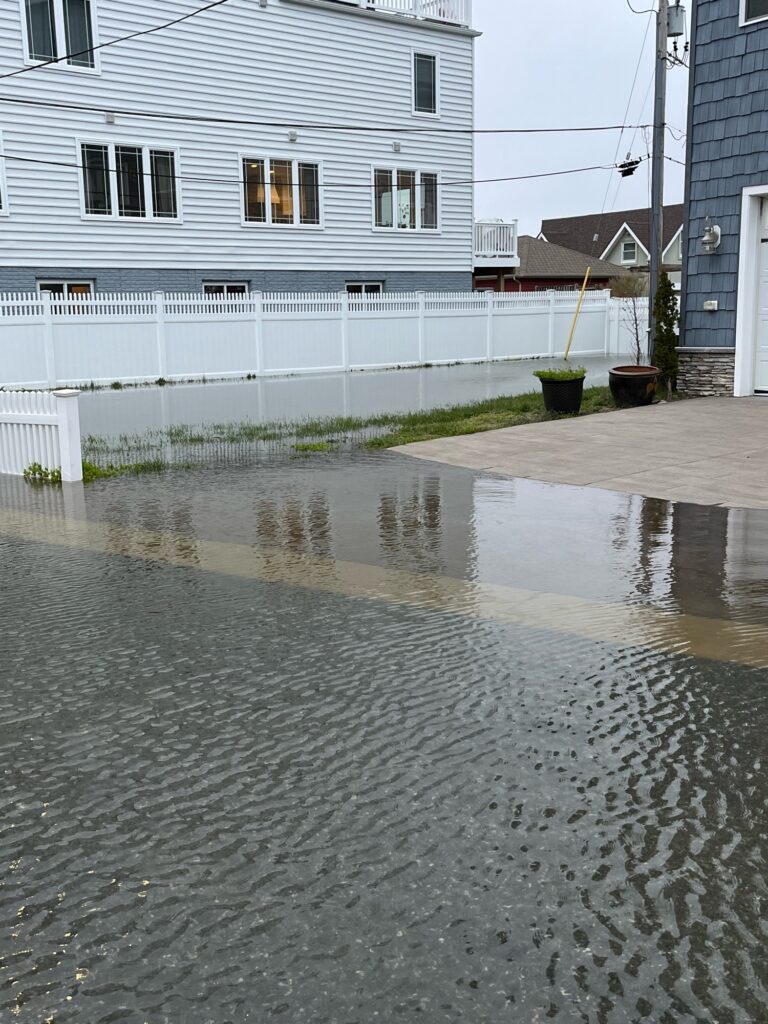 a wet street with a white fence and a white house (MyCoast AI)