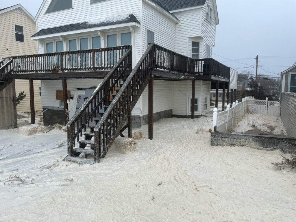 a house with a deck and a railing in the snow (MyCoast AI)
