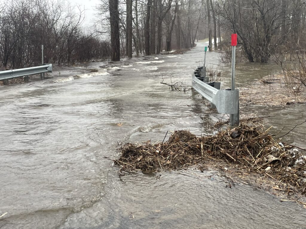a flooded road with a bench and a sign (MyCoast AI)