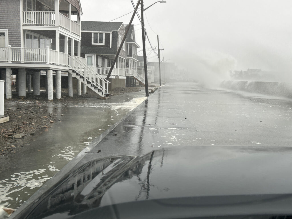 a flooded street with houses and a car driving on it (MyCoast AI)