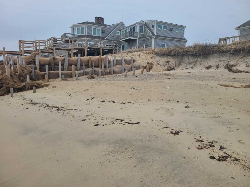 a sandy beach with a fence and houses in the background (MyCoast AI)