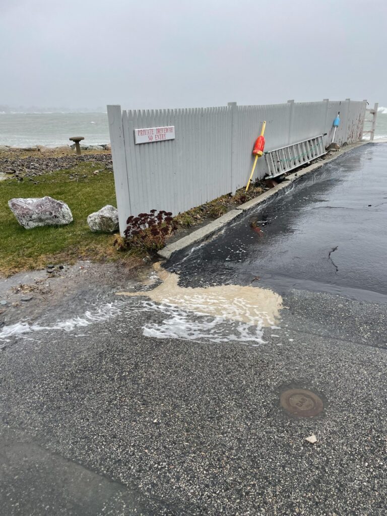 a concrete wall with a fence and a beach with a sign (MyCoast AI)