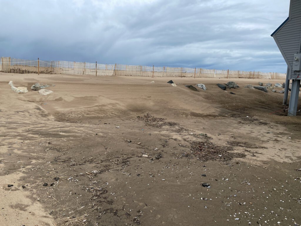 a muddy area with a fence and a building in the background (MyCoast AI)