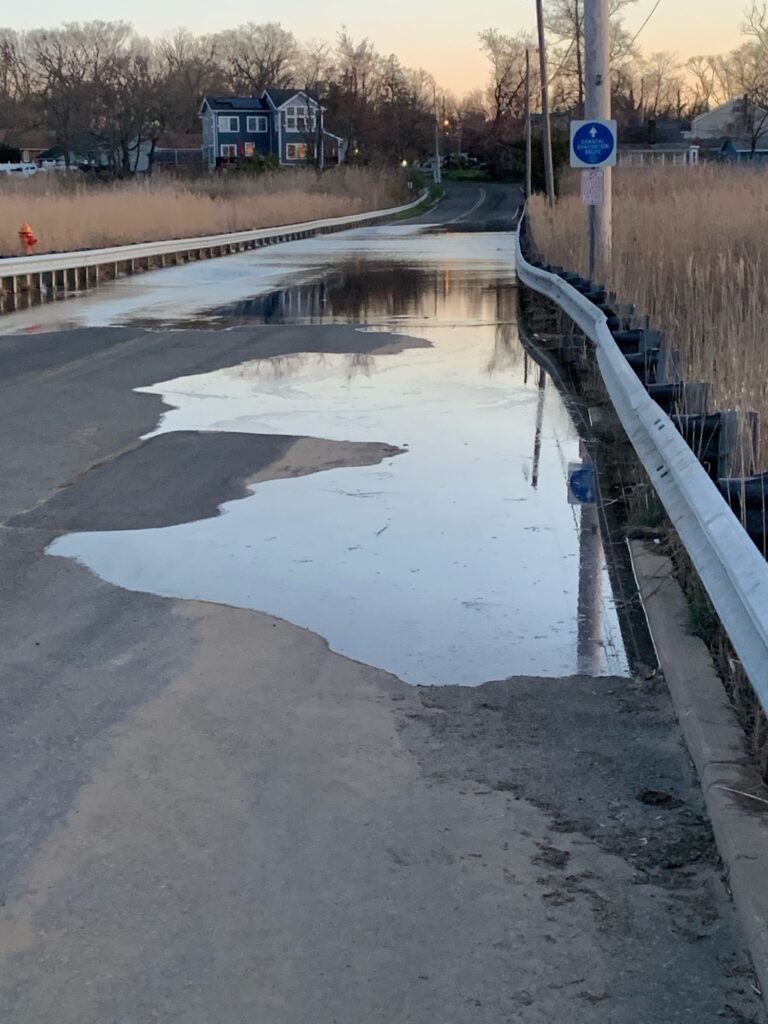 a wet road with a puddle on the side (MyCoast AI)