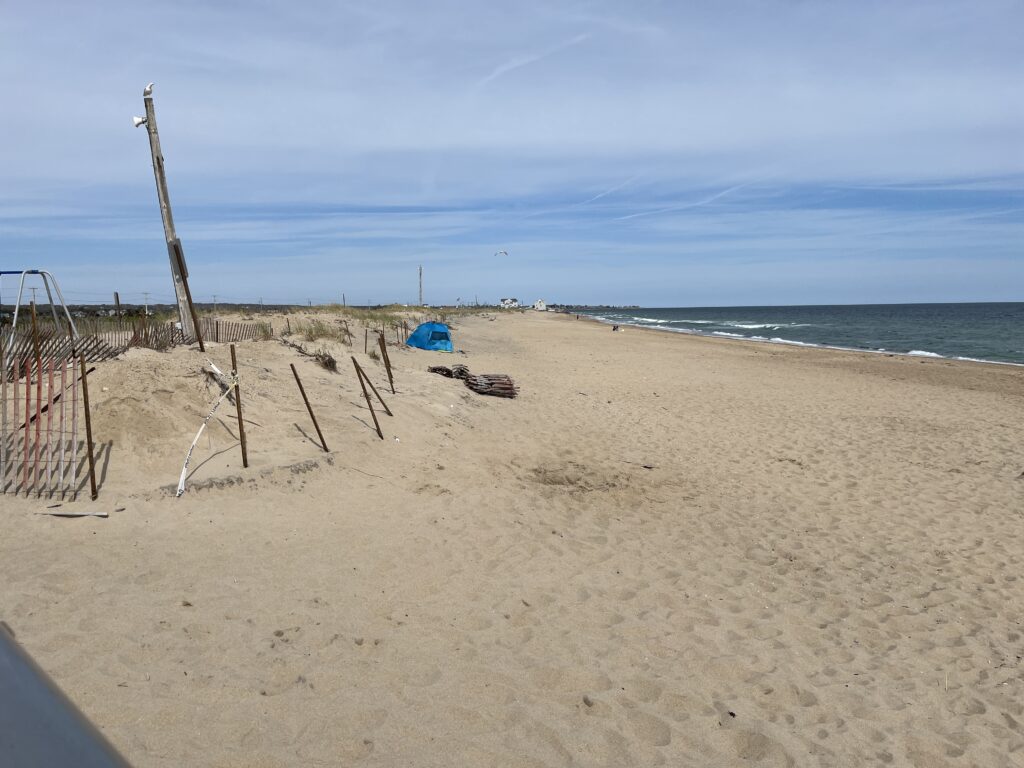 a sandy beach with a net and a blue tent (MyCoast AI)