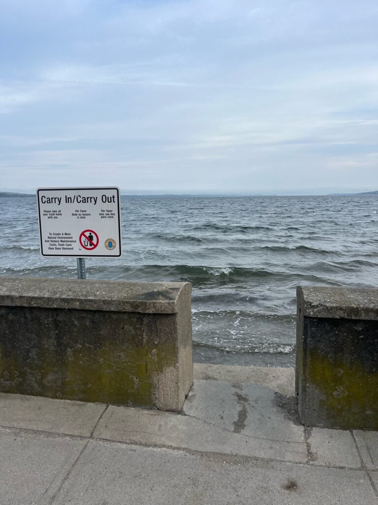 a sign on a concrete wall by the ocean (MyCoast AI)