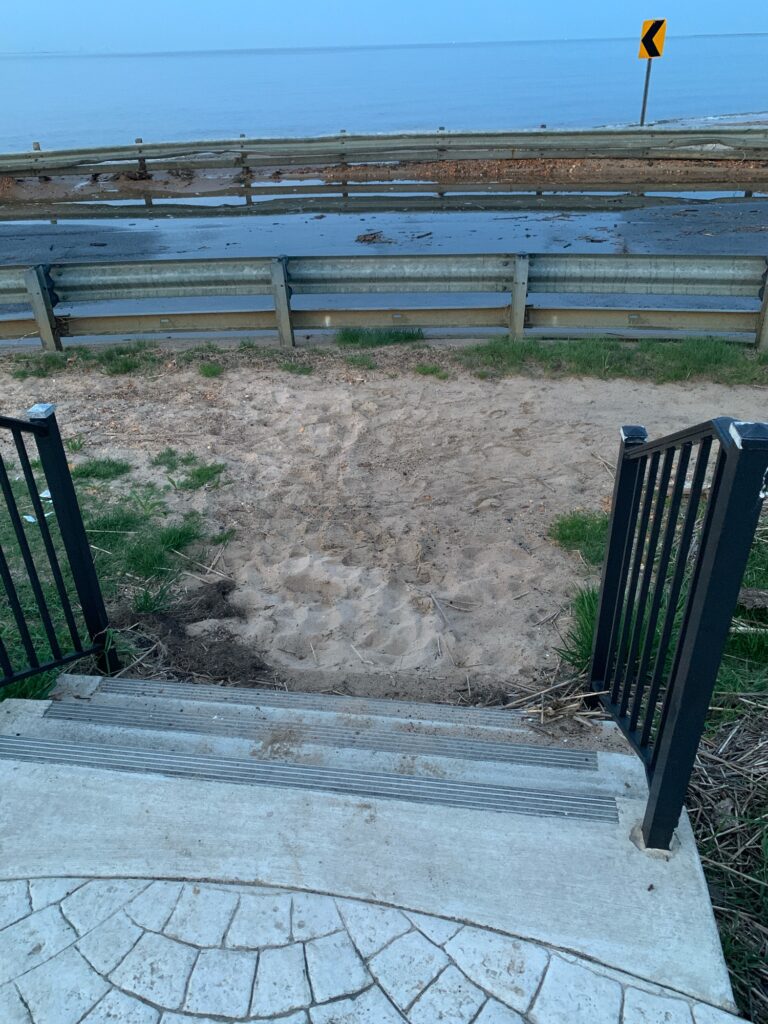 a dirt path with a fence and a body of water in the background (MyCoast AI)
