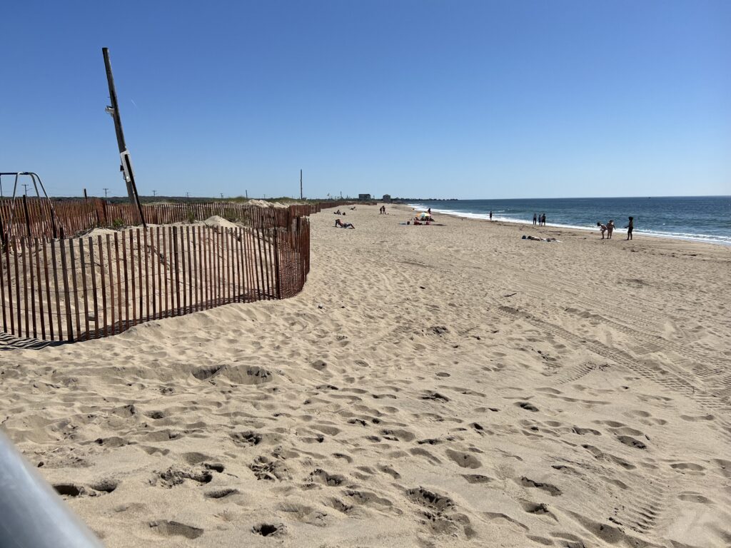 a sandy beach with a fence and people walking on it (MyCoast AI)