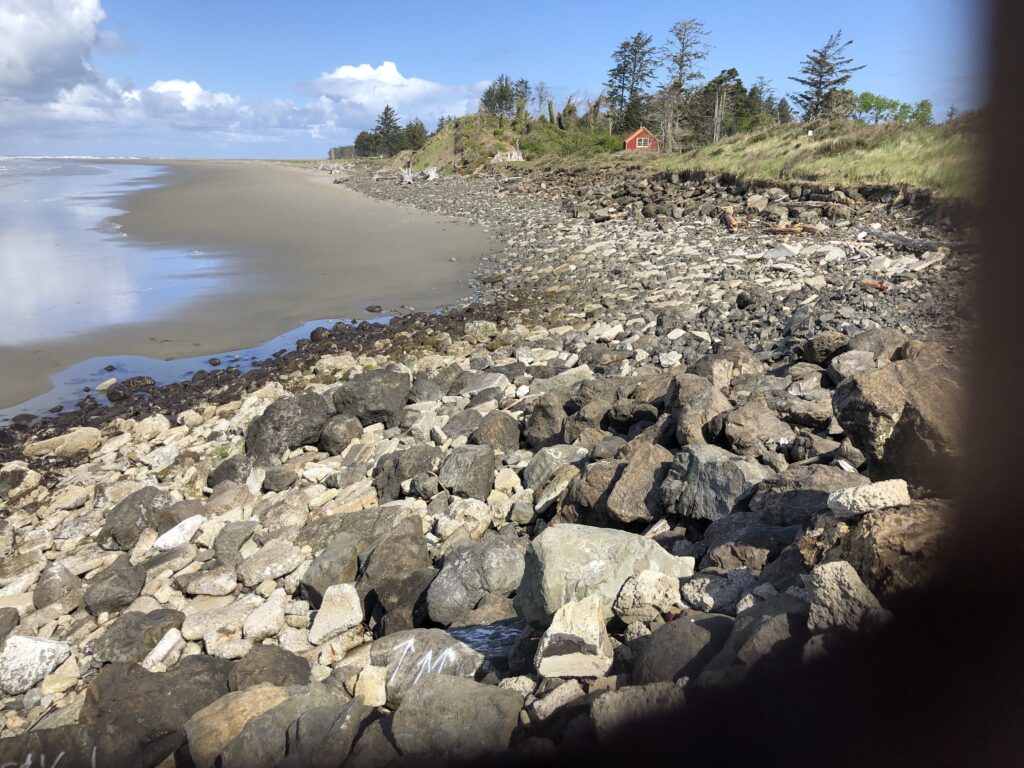 a rocky beach with a house in the background (MyCoast AI)